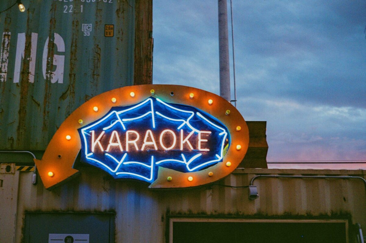 A neon sign of the word 'Karaoke' inside a spider web.